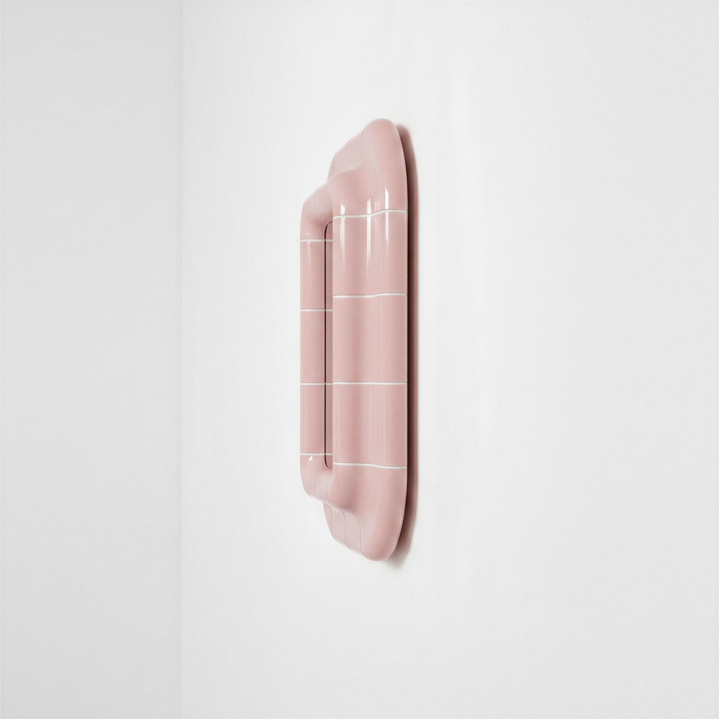 Side view of the blush pink ceramic-look mirror showing its depth and curved frame.