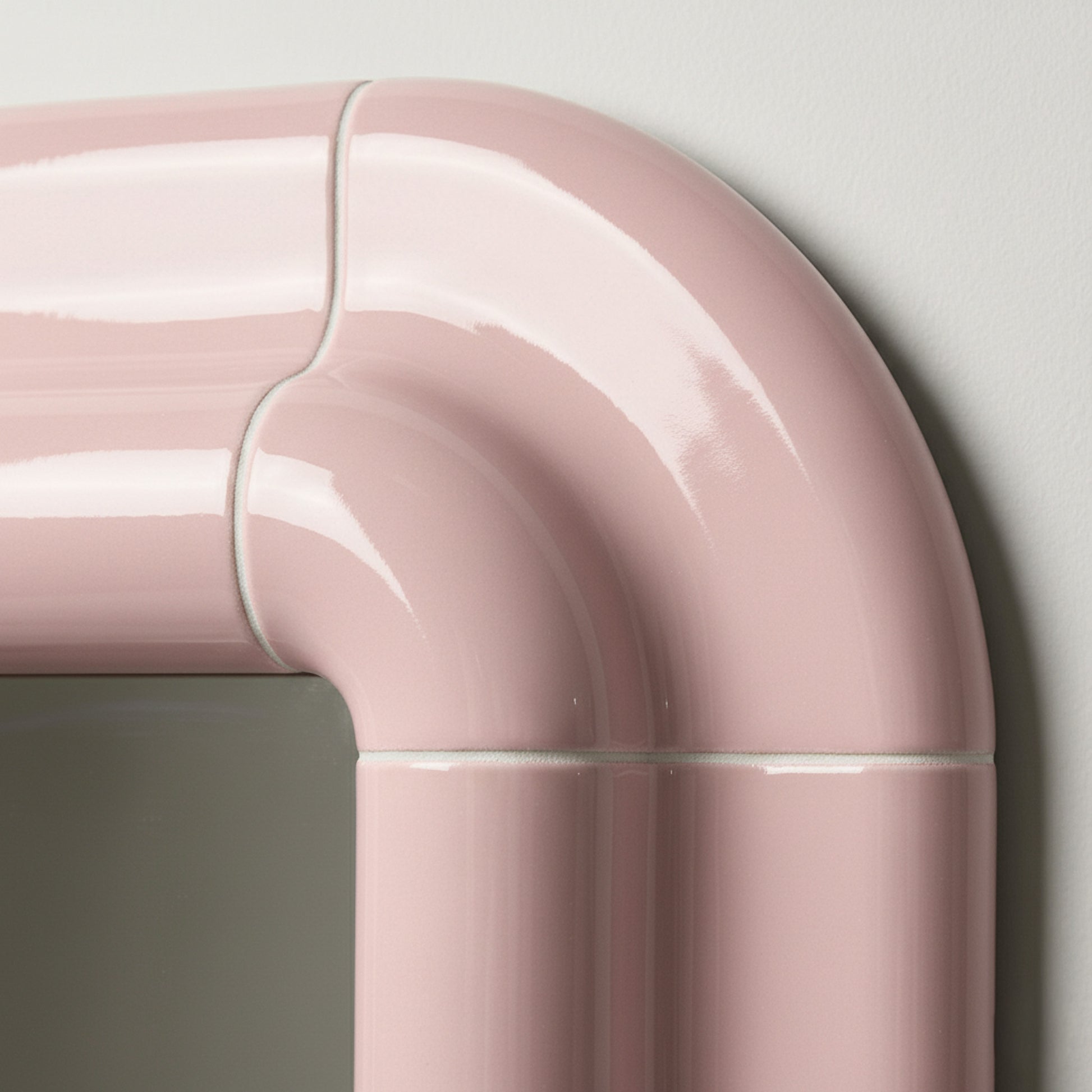 Detail of Lolo mirror in Blush Pink by Tilecito, rounded corner with high-gloss tile-inspired surface and visible grout-style lines.