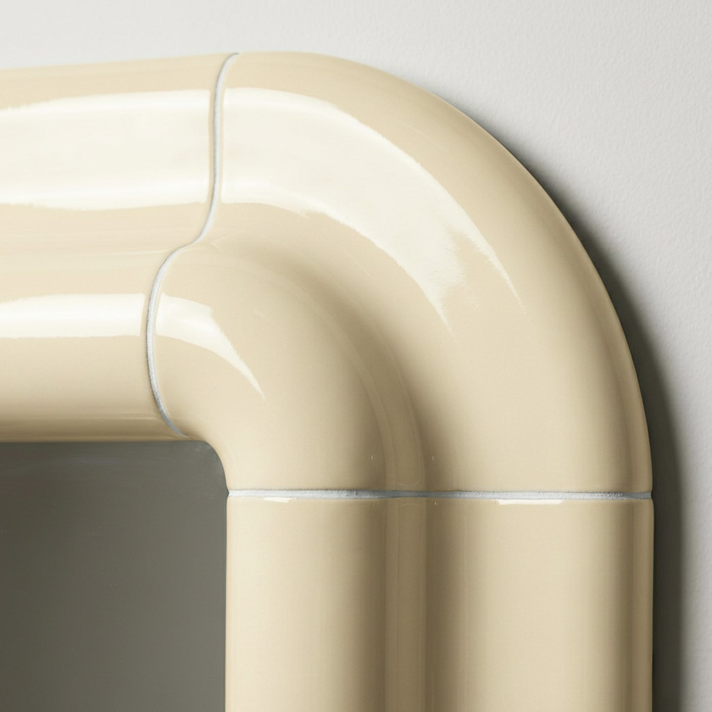Detail of Lolo ceramic mirror in Soft Beige by Tilecito, rounded glazed tile corner with visible grout lines and high-gloss finish