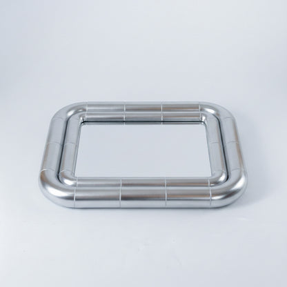 Portalito Steel mirror lying flat, showing the rounded corners and continuous tubular frame from above