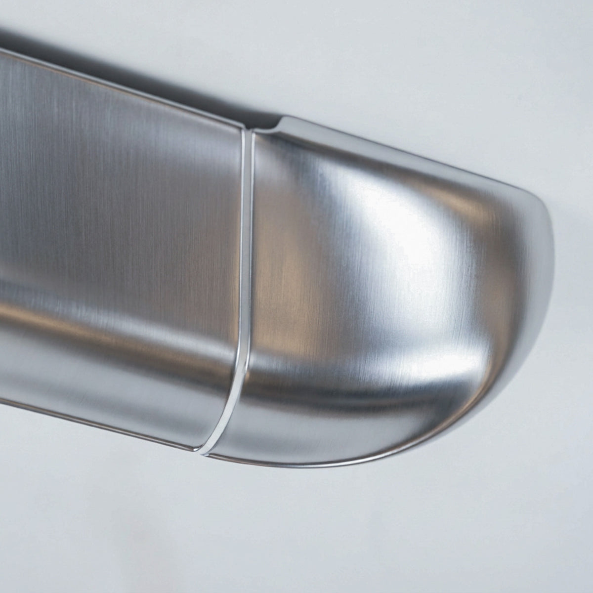 Detail of the Orbi shelf's curved end module, showing the high-gloss silver lacquer and white joint line